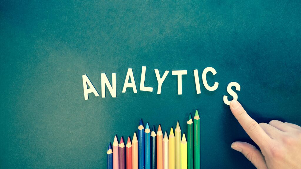pexels photo 185576 185576 Colored pencils and letters spelling 'ANALYTICS' on a textured background with a hand.